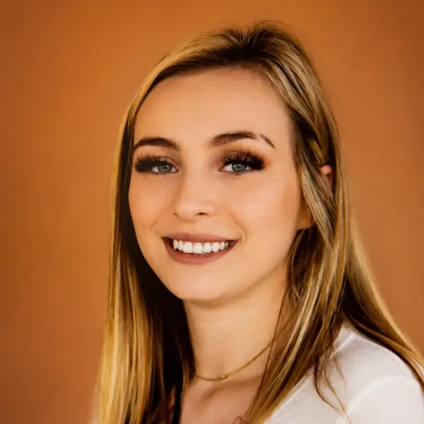 Smiling blonde woman against warm orange background